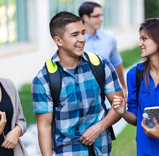 High school or college friends laughing together between classes High school or college friends laughing together between classes